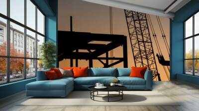 Detail vertical image of large construction crane and a iron beam frame in silhouette at sunset or sunrise Wall mural