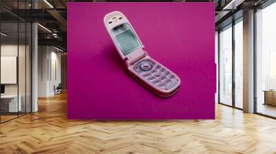 cool and classic pink retro flip cell or mobile phone isolated against a red background Wall mural