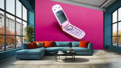 Cool and classic pink retro flip cell or mobile phone isolated against a red background Wall mural