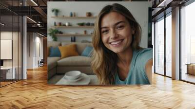 Selfie picture of a happy young pretty millennial woman smiling at the camera in the living room in a modern home
 Wall mural