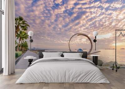 Molos Promenade and skyline of the coast in Limassol city in Cyprus at cloudy sunrise. View of boardwalk pier path landmark with palm trees, sculpture, the Mediterranean sea and people walking.	
 Wall mural