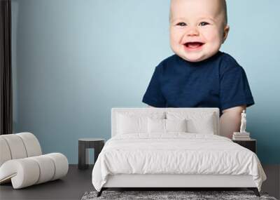 chubby little kid in t-shirt and red shorts, barefoot. he is smiling, sitting on the floor against b Wall mural