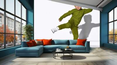 Fashion portrait of a cute little kid boy in stylish green sports suit dancing break against the white wall of the studio. Concept for sport and healthy activity for modern kid. Wall mural