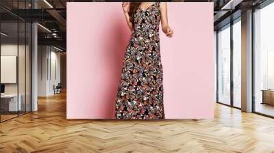 fashionable beautiful brunette girl in a long flowered dress to the floor and sneakers posing on a p Wall mural