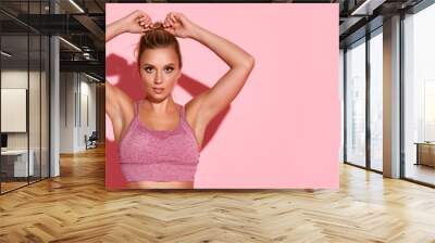 Fit and healthy woman. Sportswoman having work out on pink background. Wall mural