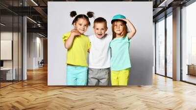 full body shot of three children in bright clothes, two girls and one boy. Triplets, brother and sisters. Wall mural