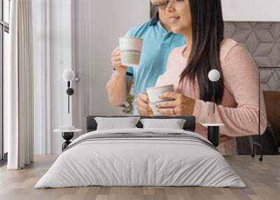 Vertical shot of a man and his pregnant partner having a drink in their apartment looking out the window Wall mural