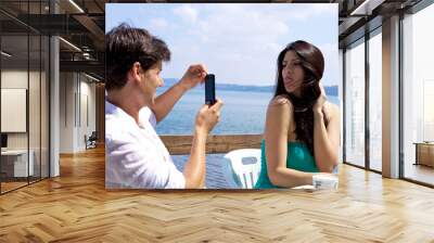 Man taking picture of beautiful wife on italian lake Wall mural