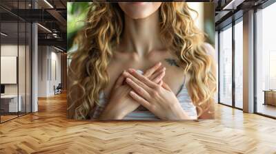 Close up of calm young Caucasian woman hold hands on heart chest feel grateful and thankful. Happy millennial female show gratitude, love and care, pray or visualize. Religion, faith concept Wall mural