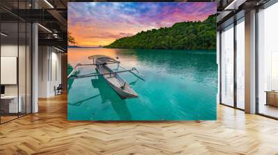 Togian Islands Indonesia sunset over caribbean sea, dramatic sky, traditional boat floating on blue green lagoon in the Togean Islands, Sulawesi, travel destination in Indonesia. Wall mural