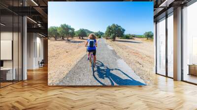 Woman riding MTB in Maremma nature reserve, Tuscany, Italy. Cycling among extensive pine forest olive trees and green woodland in natural park, dramatic coast Wall mural