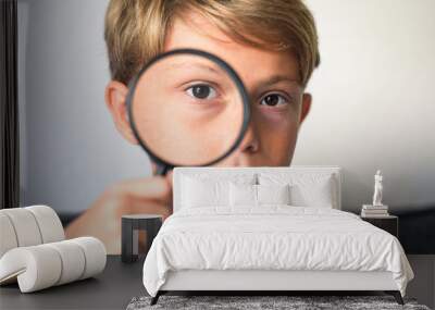 happy blond boy looking through a magnifying glass. concept of curiosity with respect to life, search for details and clues, investigating, digging observe Wall mural