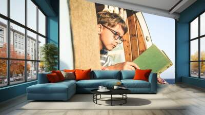 Young boy on retro mini van transport read a book Life inspiration concept with family  minivan adventure trip reading a blast relax moment Student doing homework outdoor camping holiday near the sea Wall mural