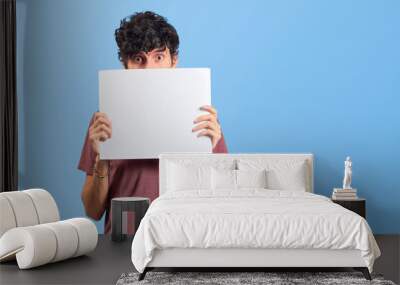 Happy young man showing a placard or advertisement on flat lay. Wall mural