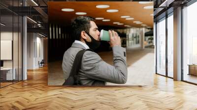 Successful young businessman walking and drinking coffee. Outdoor. Wall mural