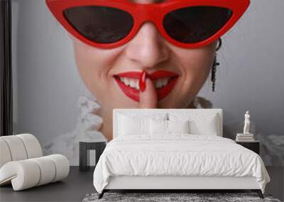 Vertical portrait of young woman wearing cat-eye sunglasses posing indoor. Wall mural