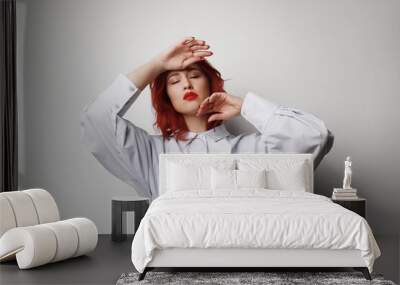 Young woman with red hair and closed eyes posing over grey background. Isolated. Wall mural