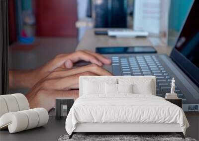 Man typing on laptop in his bedroom. Working from home, working on holiday or working from anywhere concept. Wall mural