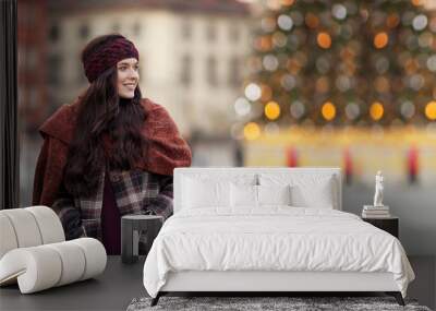 Beautiful joyful woman portrait in a city. Smiling  girl wearing warm clothes and hat  in winter or autumn. Christmas time with  unfocus lights on backgrounde. Copy space Wall mural