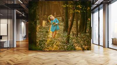 Beautiful little girl in a blue dress walking in the spring wood Wall mural