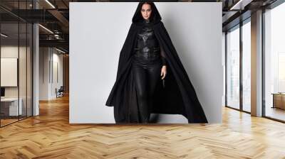 fantasy portrait of a woman with red hair wearing dark leather assassin costume with long black cloak. Full length standing pose  isolated against a studio background. Wall mural