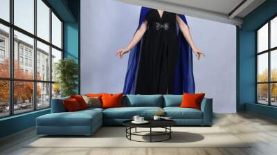 Full length portrait of  female red head model wearing  glamorous black witch dress with blue fantasy cloak halloween costume.  standing pose with gestural arms, isolated figure studio background. Wall mural