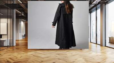 Full length portrait of pretty young asian girl wearing black tank top, utilitarian  pants, leather boots and large dark coat. Standing pose with gestural hand movements,  isolated on  studio backgrou Wall mural