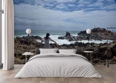 portrait of female model  standing wearing white goddess dress, dramatic natural landscape background of rocky ocean shoreline with stone clifftops. castle rock, Busselton, Western Australia Wall mural