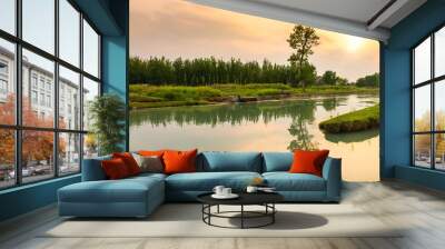 Panorama of a river surrounded by greenery with trees reflecting on the water during the sunset Wall mural