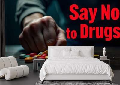 Say No to Drugs. A hand, partially obscured by shadow, reaching for a pile of colorful pills on a wooden table. This image conveys a powerful message against drug abuse and addiction Wall mural