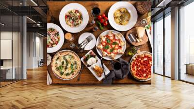 Big dinner table with italian food, pizzas and pastas Wall mural