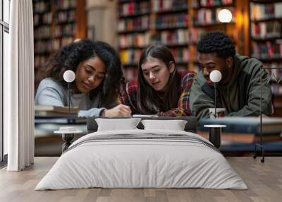 Three focused diverse students collaborate on their studies in a well-lit library Wall mural