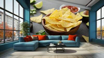 Tortilla chips in a bowl with salsa, limes and avocados Wall mural