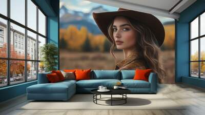 Beautiful Woman in a Cowboy Hat Against a Scenic Mountain Background with Autumn Colors for a Stylish and Sophisticated Portrait Wall mural