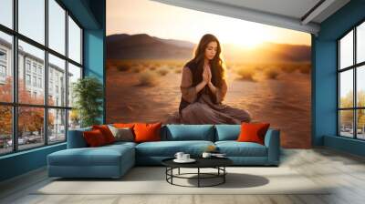 Christian woman kneeling and praying in the desert, at sunset. Biblical Wall mural