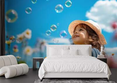 Little girl blowing soap bubbles in the field with flowers on blue sky background Wall mural