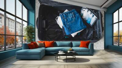 packing light for a holiday concept, luggage with pile of clothes next to transparent liquid bag for airport security screening compliance Wall mural