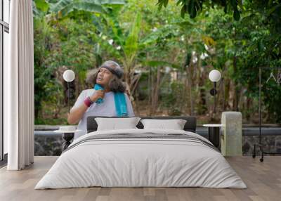 An adult Indonesian asian man with curly hair  sitting down to rest after a morning run, the concept of a healthy lifestyle through Wall mural