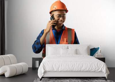 Asian male construction worker in full dress is on a phone call while carrying a clipboard, industrial and construction concept, isolated on white background. Wall mural