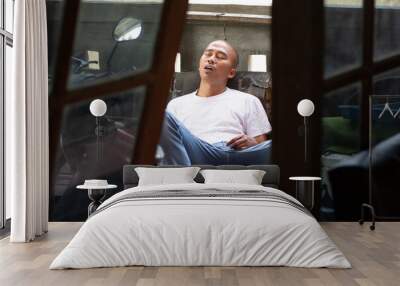 Asian man with bald head falling asleep on a chair in a sitting position with his mouth open caused by being exhausted. Wall mural