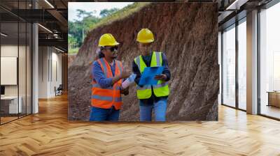 Two young male construction workers are surveying using blueprints in the field Wall mural