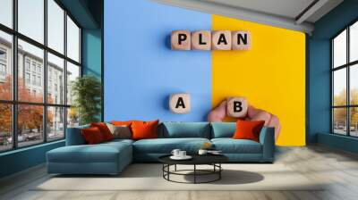 The hand of a businessman choosing business plan B out of two options on a yellow and blue background. Business strategy and decisions concept. Wall mural