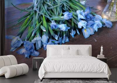 Floral business concept. Blue lovely iris flowers with long stems on dark wooden table in flower shop. Creates professional bunch in floristic studio store. Wall mural