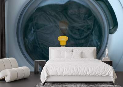 Yellow sandglass on window of washing machine with grey bedspread inside is working, laundry at home. Modern technologies in everyday life, housework and household. Wall mural