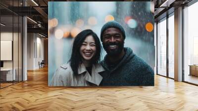 A cheerful couple smiles brightly at the camera while standing together on a busy city street under the rain with blurred, colorful lights behind them. Wall mural