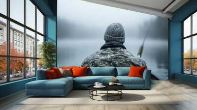 A peaceful depiction of a fisherman in camouflage, casting his line into a fog-covered lake, conveying tranquility and connection with nature in a misty morning scene. Wall mural