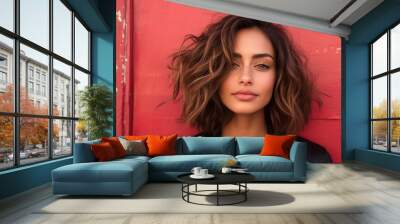 A woman with short styled brown hair poses against a striking red background, embodying self-assurance and modern beauty in an artistic composition. Wall mural