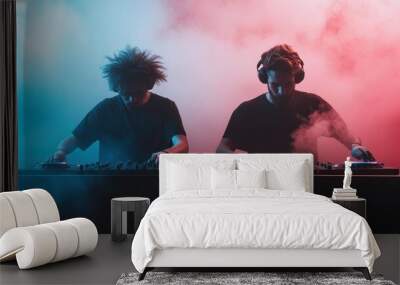 Two DJs are performing on stage, surrounded by swirling red and blue smoke, creating a vibrant and dynamic atmosphere in a modern club setting. Wall mural