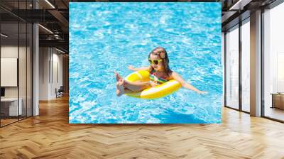 Child in swimming pool on ring toy. Kids swim. Wall mural