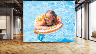 Child in swimming pool on toy ring. Kids swim. Wall mural